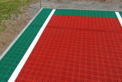 Als Oberbelag wurde ein perforierter Hart-Kunststoffbelag, aus UV- und vwitterungsbeständigem Polypropylen (PP) Kunststoff, in  den Farben Ziegelrot und Grasgrün, ausgewählt und schwimmend verlegt.