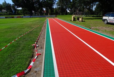 Zunächst erfolgte der frostbeständige Unterbau, mit Bodenaushub und Schotterauffüllung und Planum aus Edelsplitt 02. Auf einer Seite wurde eine Drainage auf ganzer Länge installiert. Darauf folgte der 12 mm starke Gummibelag und Verklebung der Stöße mit F