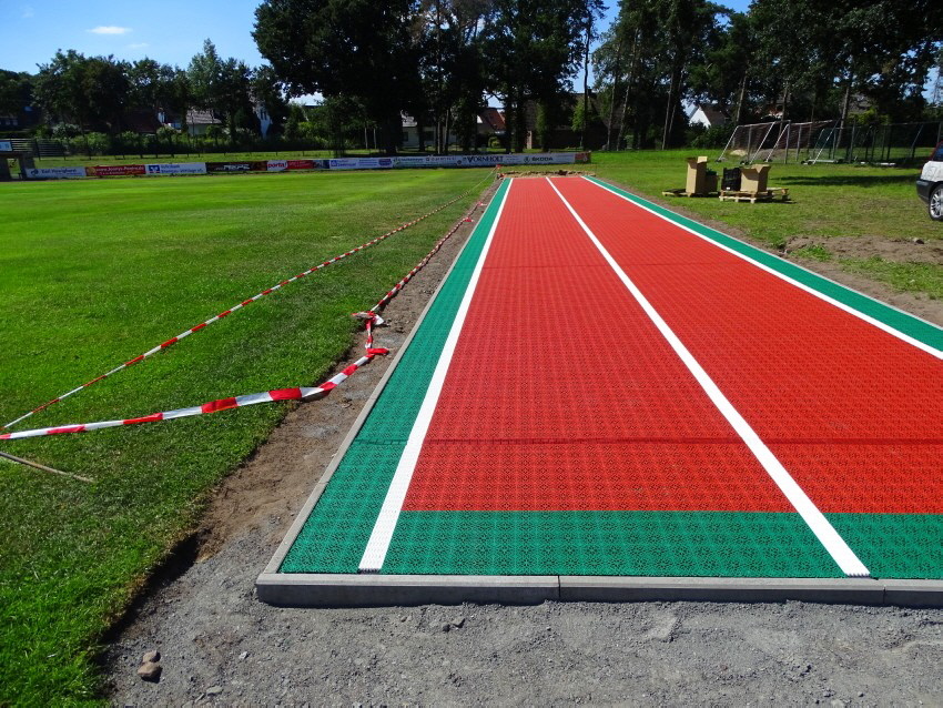 Zunächst erfolgte der frostbeständige Unterbau, mit Bodenaushub und Schotterauffüllung und Planum aus Edelsplitt 02. Auf einer Seite wurde eine Drainage auf ganzer Länge installiert. Darauf folgte der 12 mm starke Gummibelag und Verklebung der Stöße mit F
