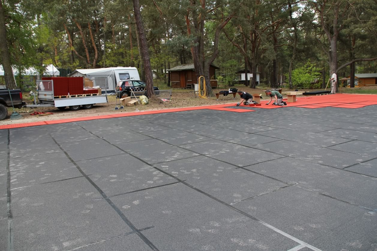 Installation der Gummi-Abdeckung für den Tennis-Allwetterplatz